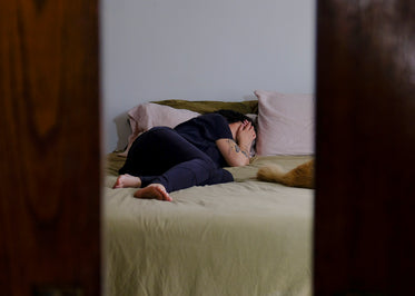 person lays in bed and holds a hand up to their face