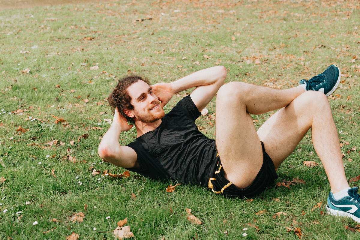 person lays on grass and crunches in a situp