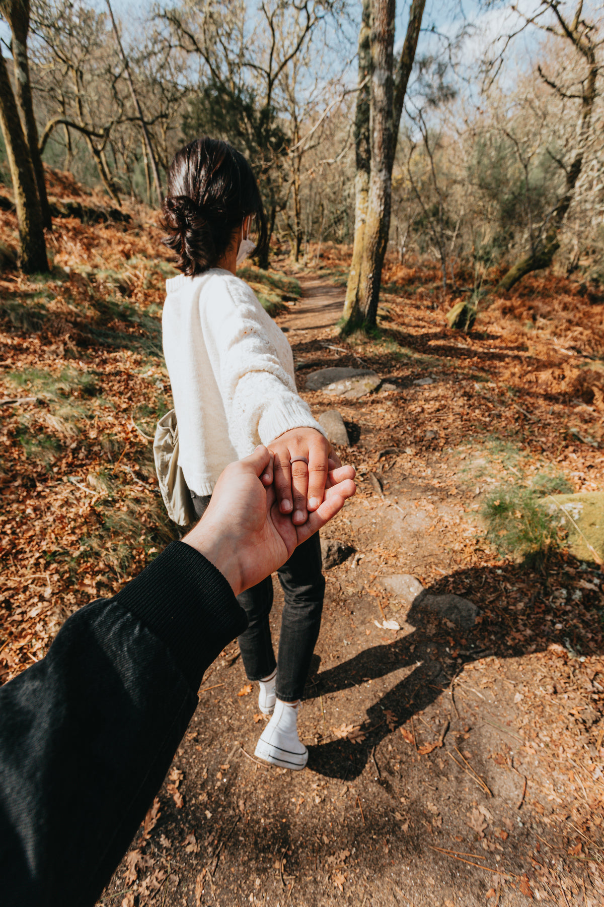 person leads someone by the hand down a hiking trail