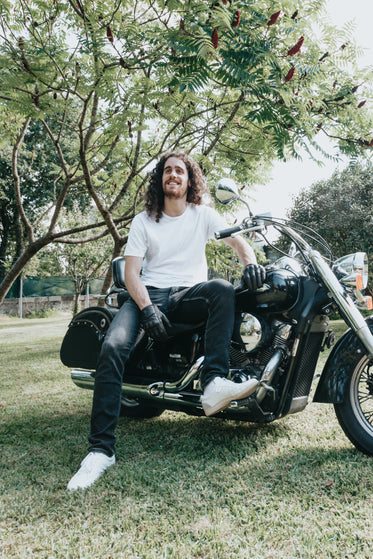 person leans on a motorcycle on green grass