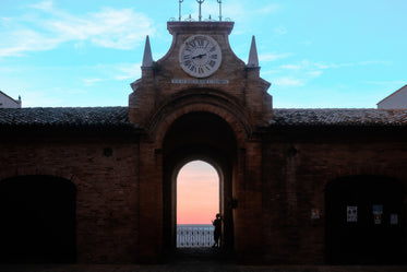 person leans on archway wall and takes in the sunset