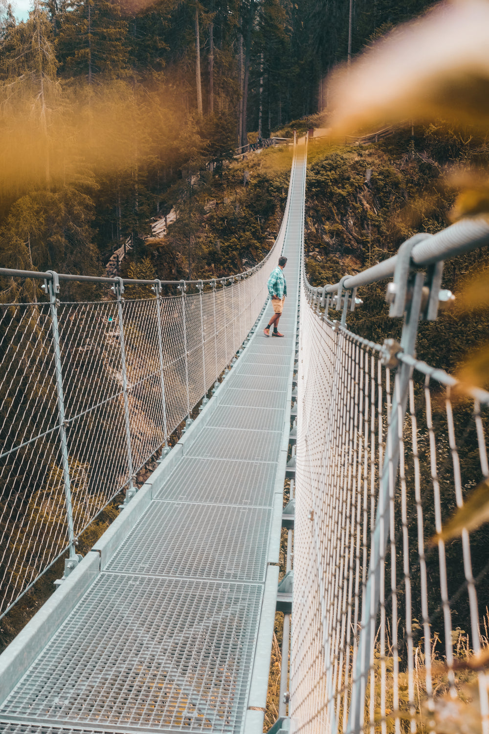 person looks back while walking on a bridge