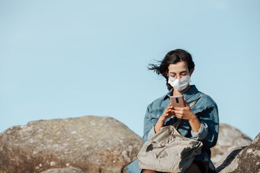 person looks down at their cellphone while sitting outdoors