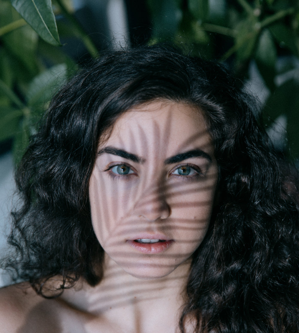 person looks forward with the shadow of a leaf on their face