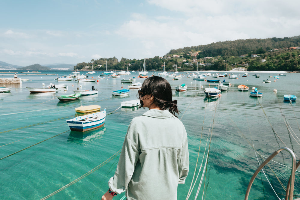 person looks out to aqua blue water filled with boats