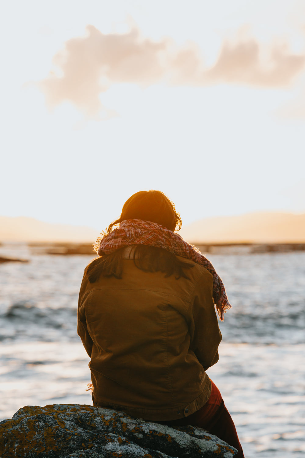 person looks out towards the ocean at sunset