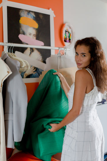 person looks over their shoulder while holding green fabric