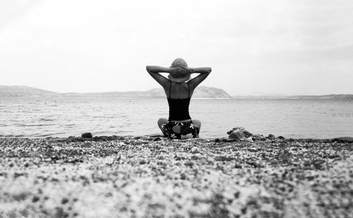 person on a beach with their hands up in black and white