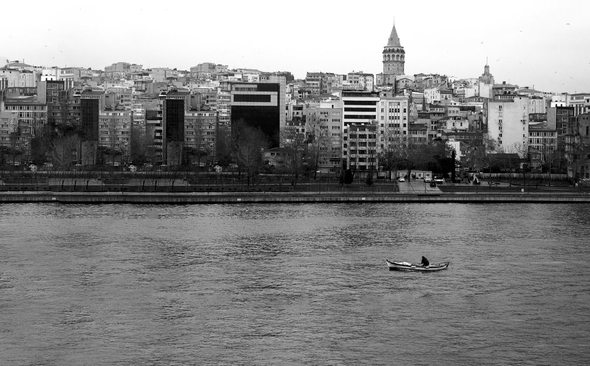 一个人在城市旁边的水中乘船