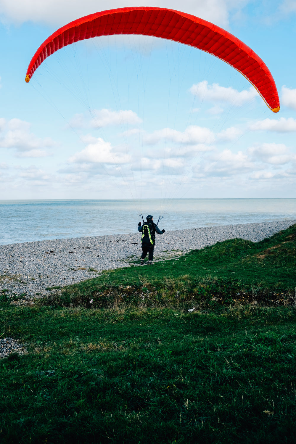 person on the shore with a red kite for surfing