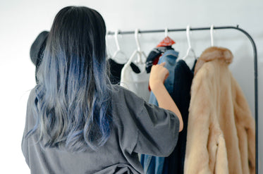 person organizes clothes on a thin clothing rack