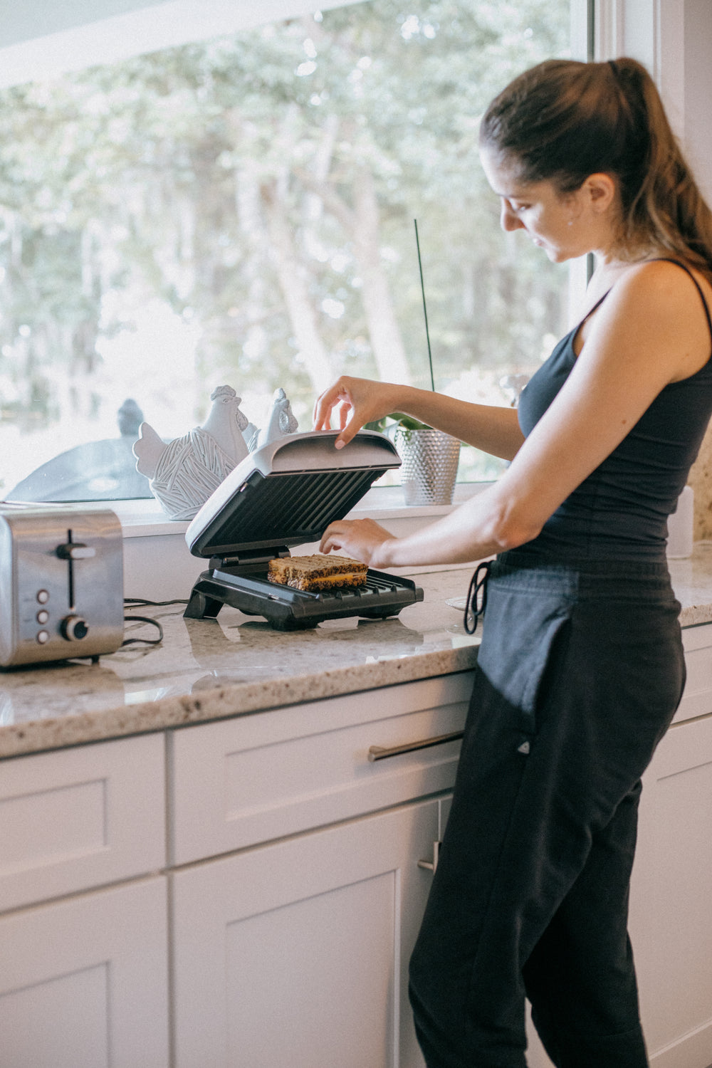 person places a sandwich into a panini press