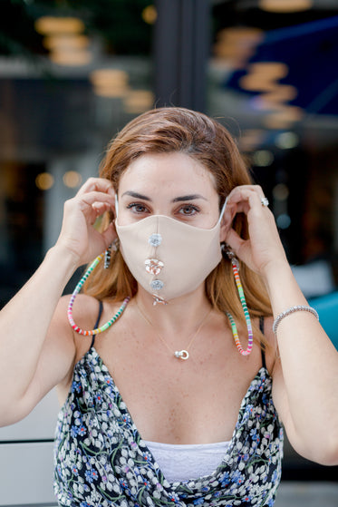 person puts on face mask with sequin flower