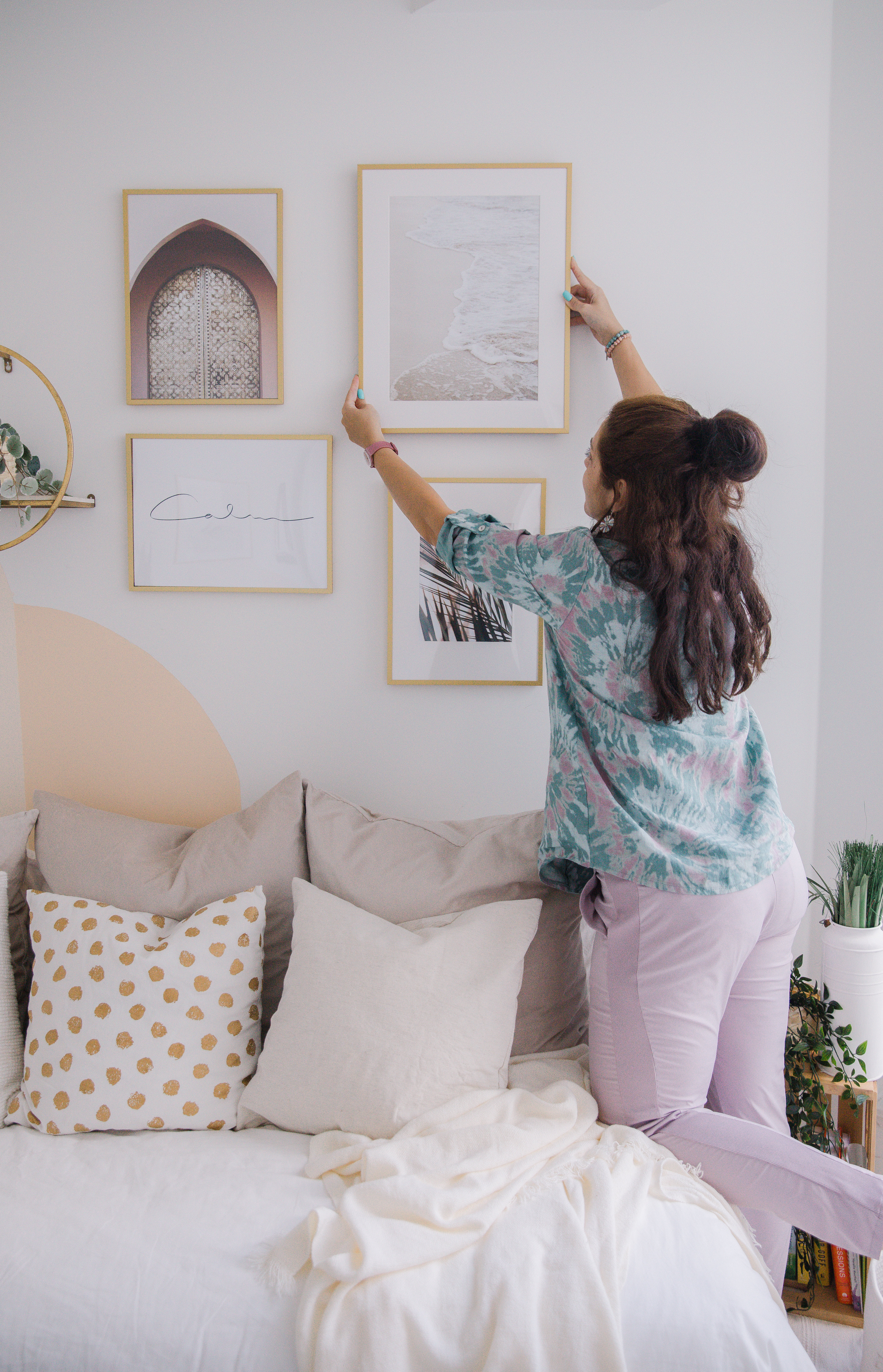 Person Reaching To Hang A Frame On The Wall