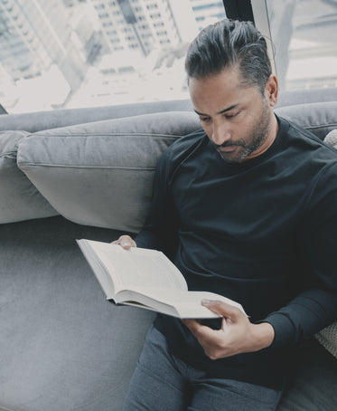 person reading a novel on the couch