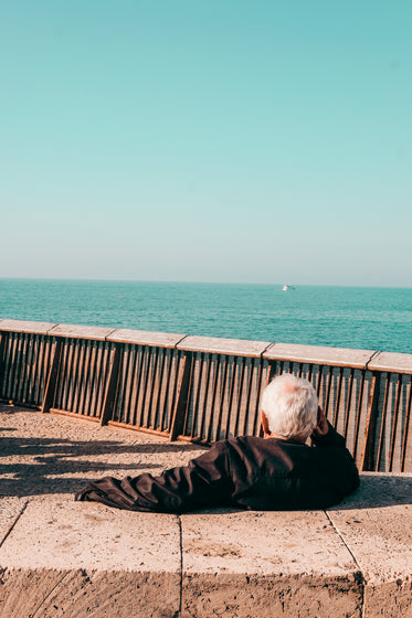 person relaxes while taking in ocean view