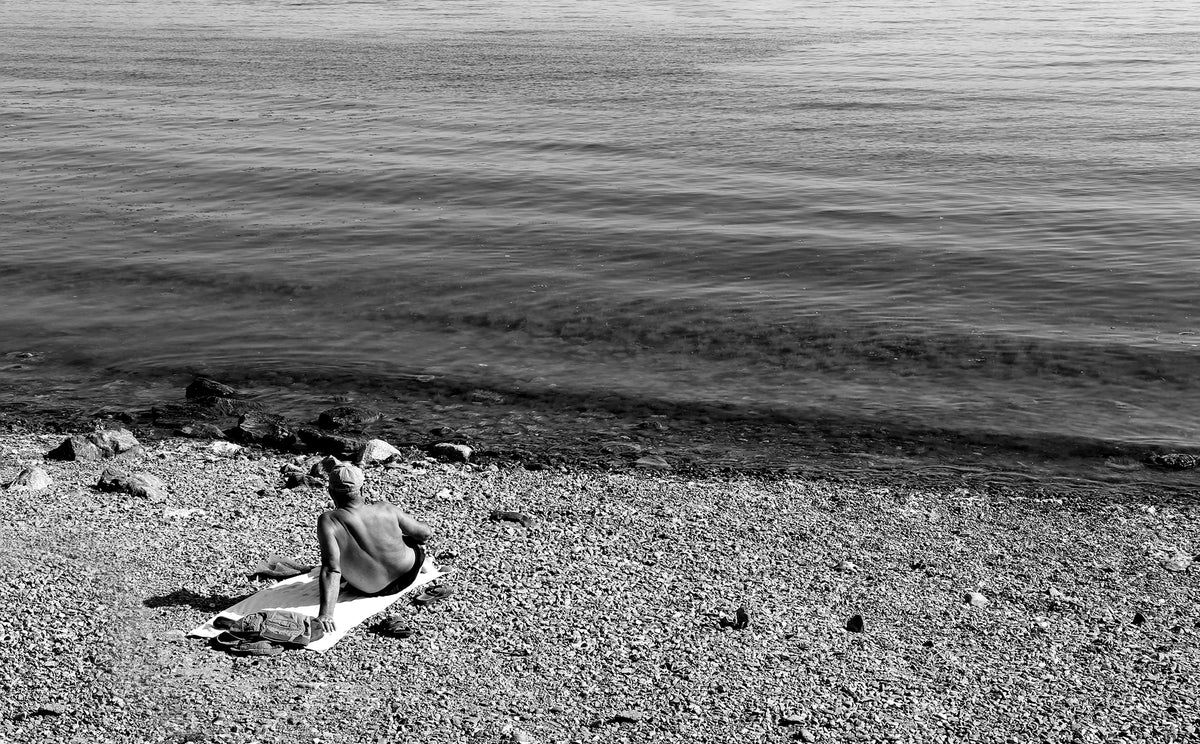 person resting on their beach towel in black and white