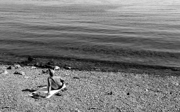 person resting on their beach towel in black and white