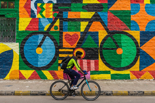 person rides a bike with a mural of a bike behind them