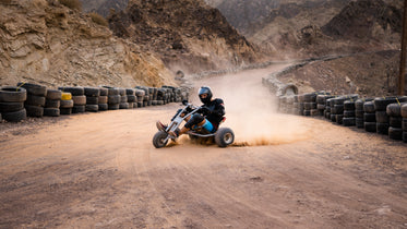 person rides a vehicle leaving a cloud of sand behind