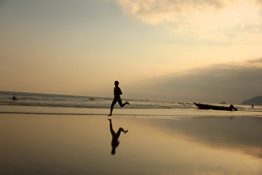 person running on the beach under setting sun