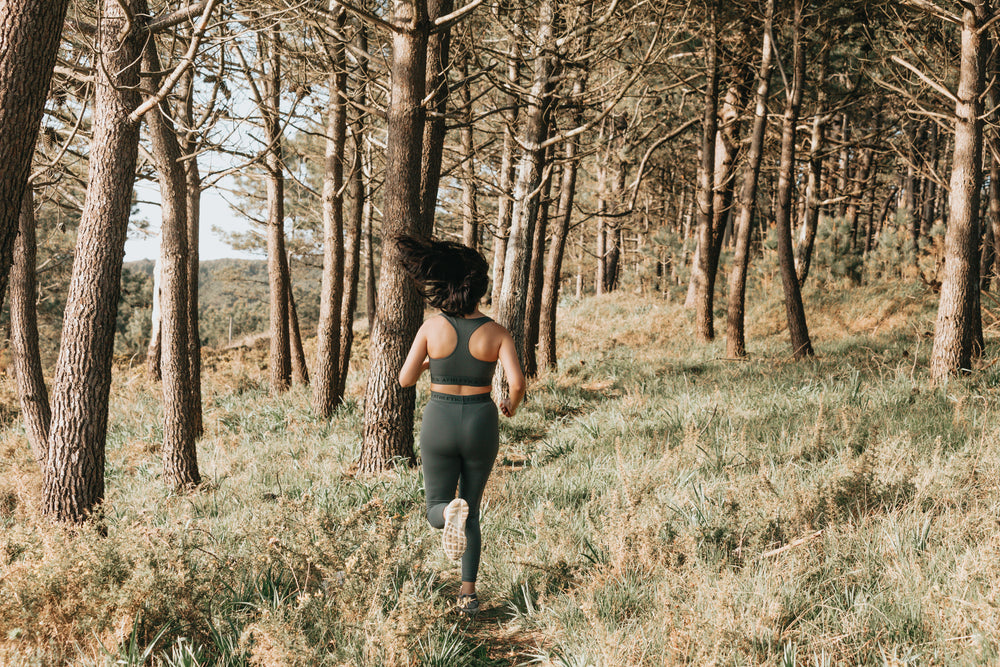 person running through a forest down a narrow path