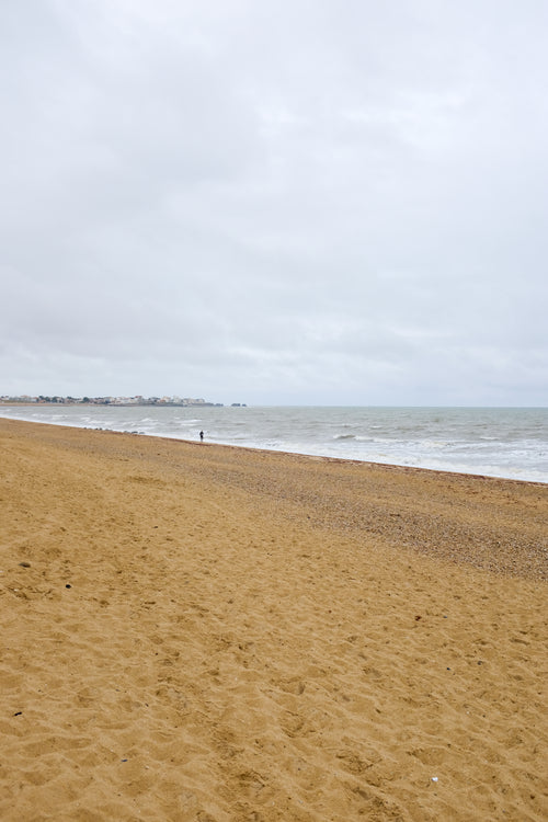 person runs on the sandy beach on a overcast day
