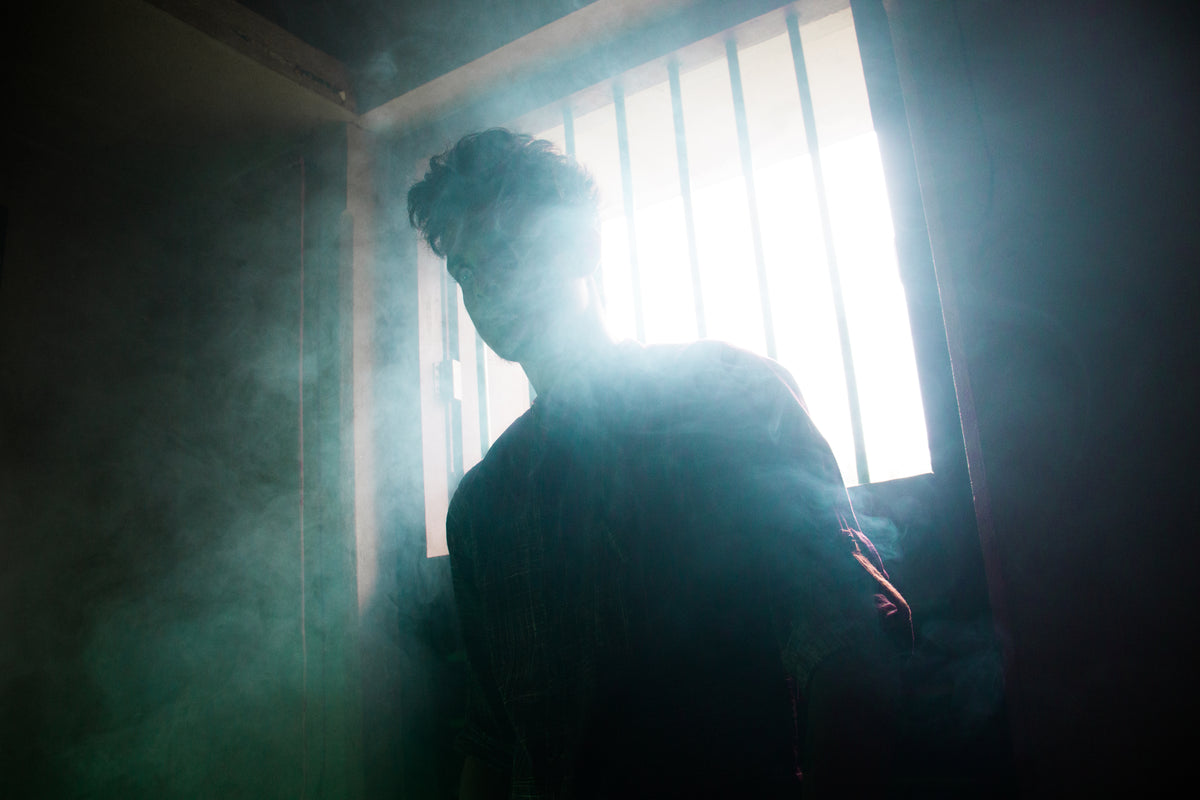 person silhouetted by a window in a smoky room
