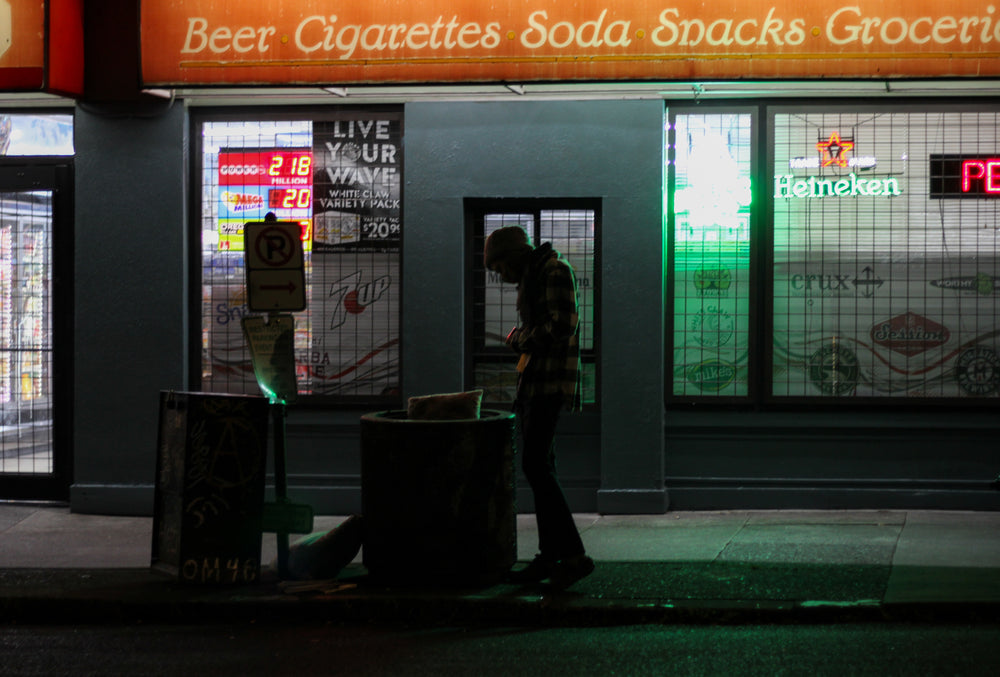 person silhouetted stands outside a grocery store