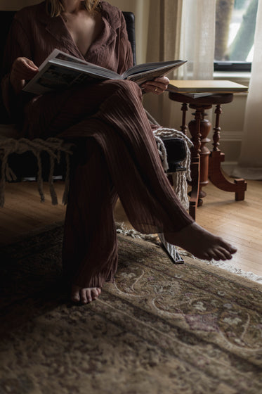 person sits cross legged reading a large book