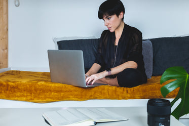 Person Sits Crossed Legged Working On Their Laptop