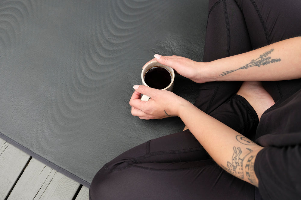 person sits cupping a mug with both hands