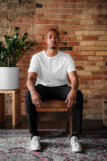 person sits facing the camera in front of a red brick wall