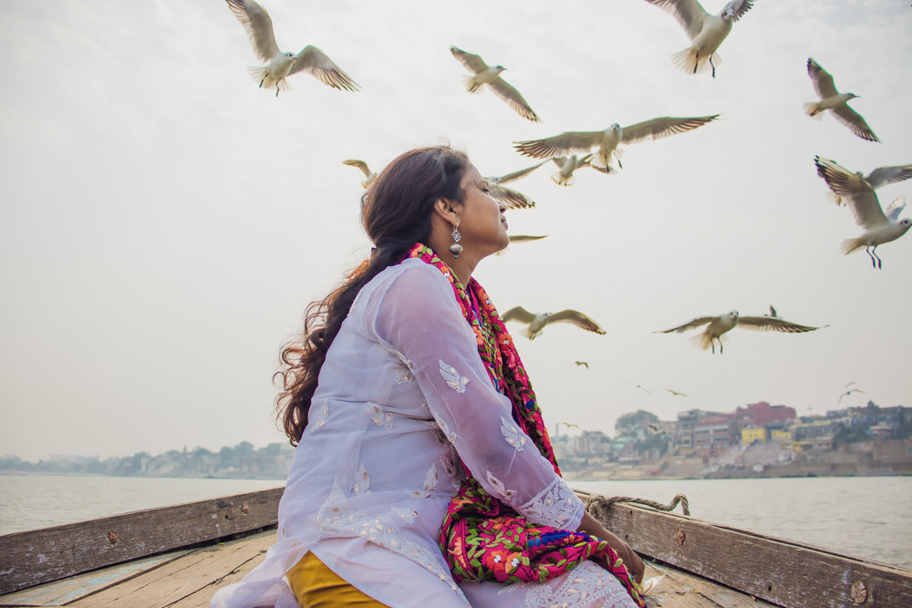 person sits in a boat looking at flying birds