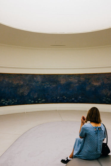 person sits in art gallery looking at painting