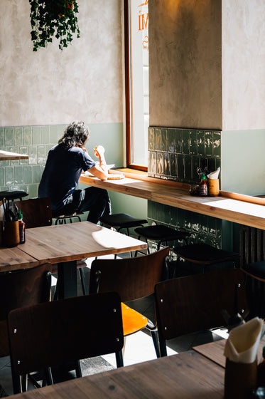 person sits in corner of cafe by a bright window