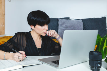 person sits in front of a laptop and takes notes