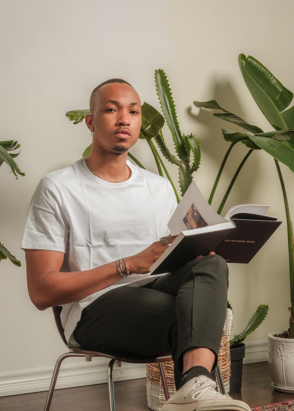 person sits in front of a wall lined with potted plants