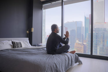 person sits in reflection at the end of their bed