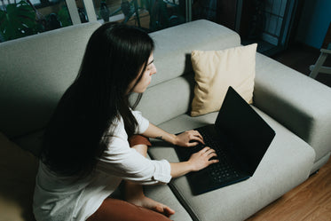 person sits on a couch typing away on laptop