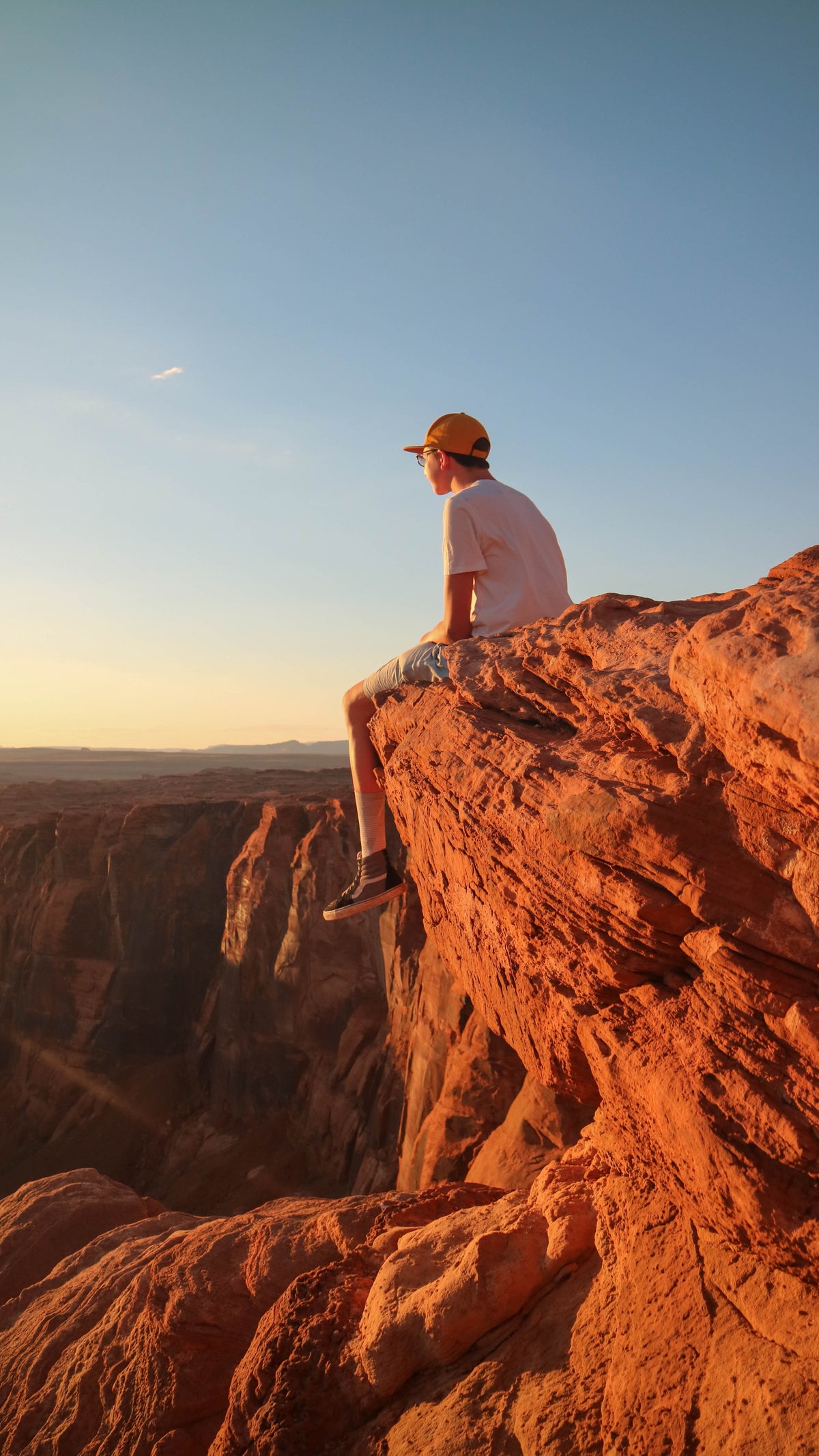 person sits on rocky peak bathed in golden light