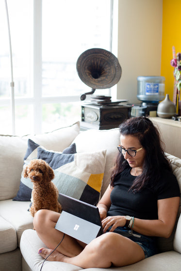 person sits on their couch next to their dog