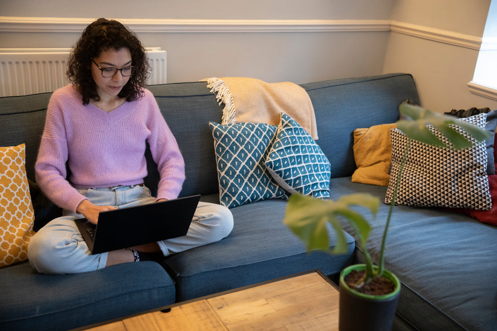 person sits on there couch working on there laptop