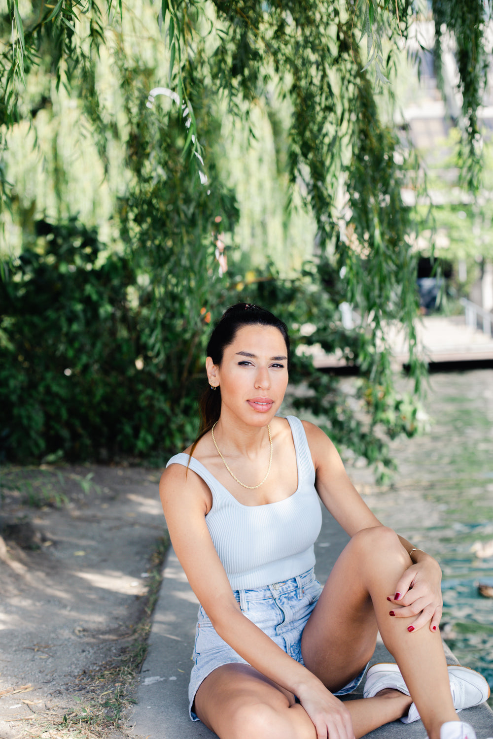 person sits under a tree with long green branches