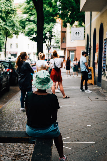 person sits waiting in line outside a shop