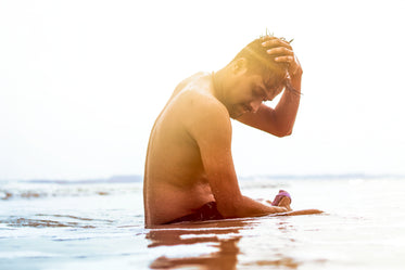 person sitting in shallow water on a sunny day