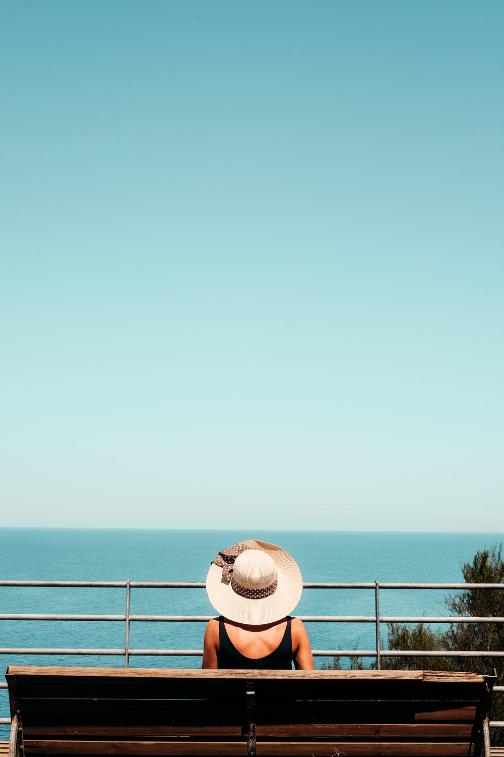 person sitting on a bench and looking out to the ocean