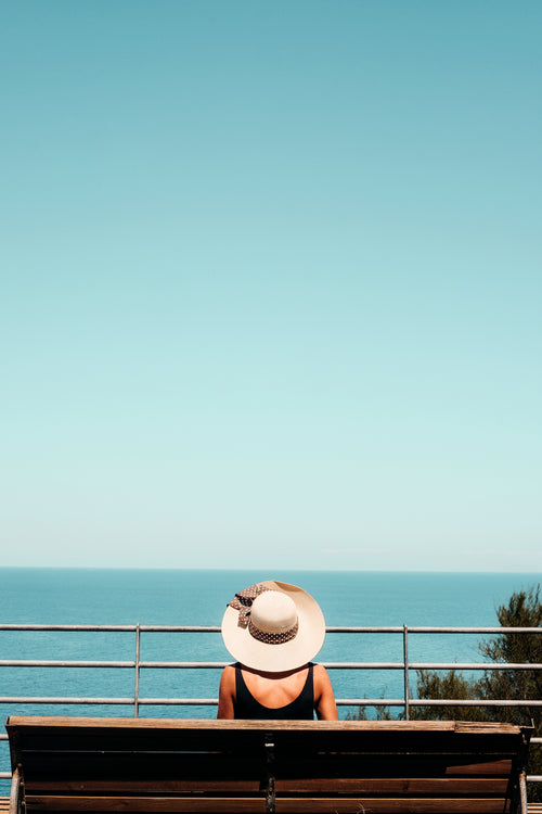 pessoa sentada em um banco observando o oceano