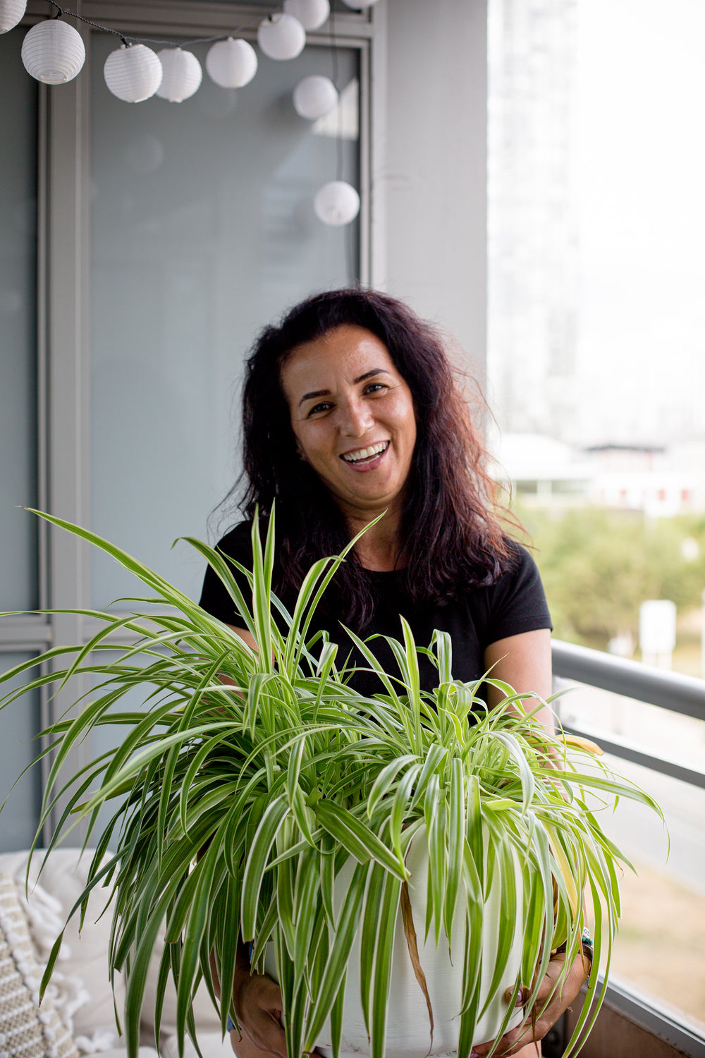 person smiles and holds a large house plant