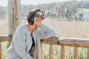 person smiles in grey sweater on bench